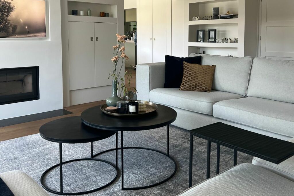 Gezellige landelijke woonkamer zwarte ronde salontafels, grijze bank en grijs vloerkleed