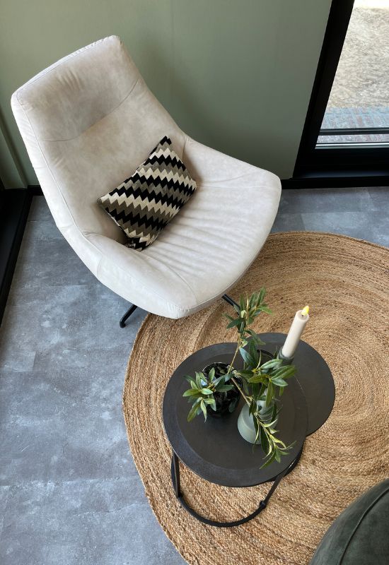 Grijze velvet fauteuil rond jute vloerkleed zwarte ronde bijzettafeltjes