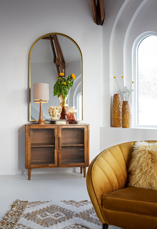 Houten dressoir met glazen deurtjes gestyled met accessoires en grote gouden spiegel