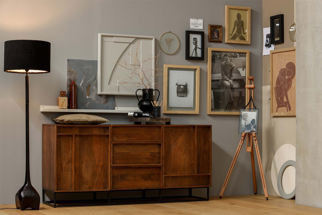 Houten dressoir met zwarte poot kunst en fotolijsten aan de muur