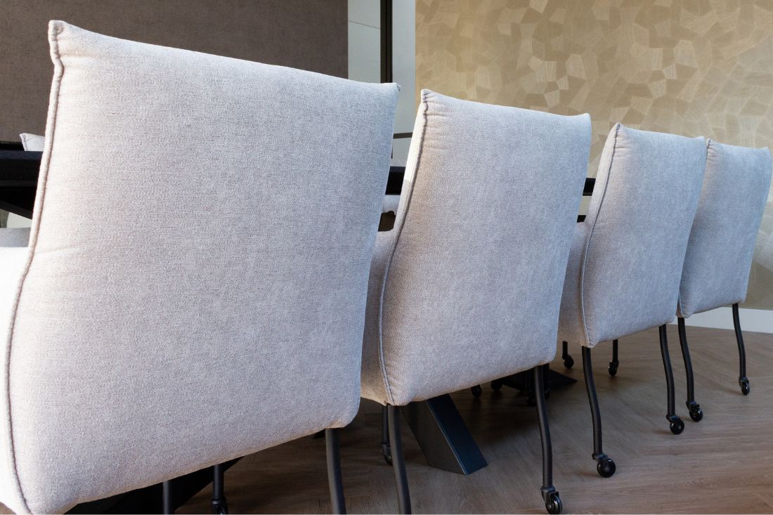 Lichtgrijze eetkamerstoelen met zwart onderstel en wieltjes