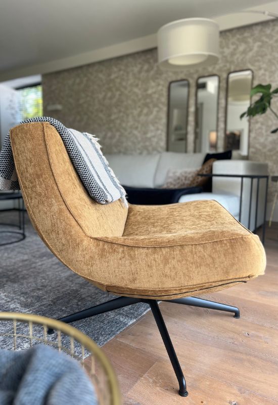 Okergele gouden fauteuil met zwarte poot op grijs vloerkleed en houten vloer