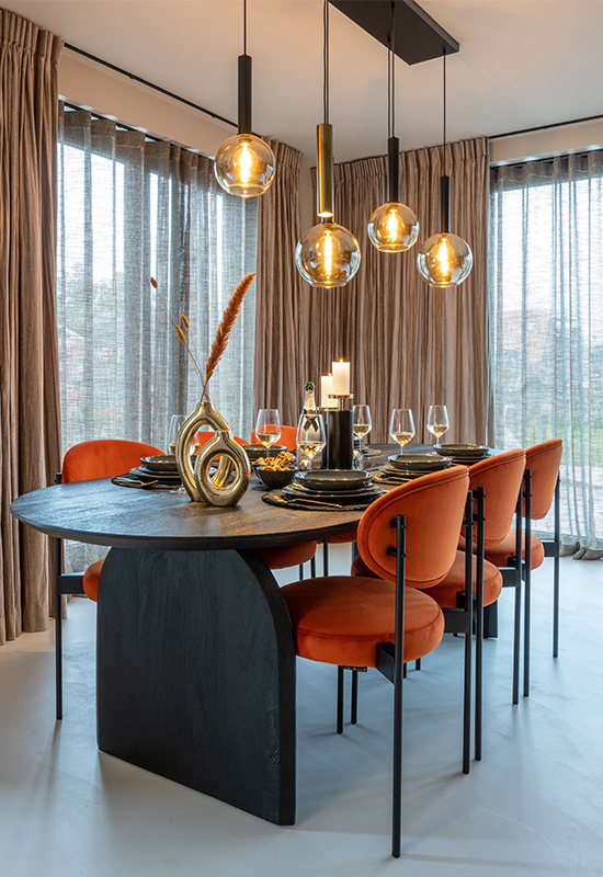 Zwarte houten eettafel met ovale poot en oranje ronde eetkamerstoelen