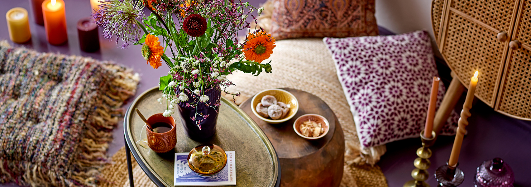 Gouden en bronzen bijzettafel bos bloemen kleurrijke sierkussens kaarsen en kandelaren