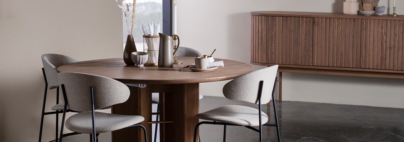 Ronde houten eettafel met grjize eetkamerstoelen met zwart frame