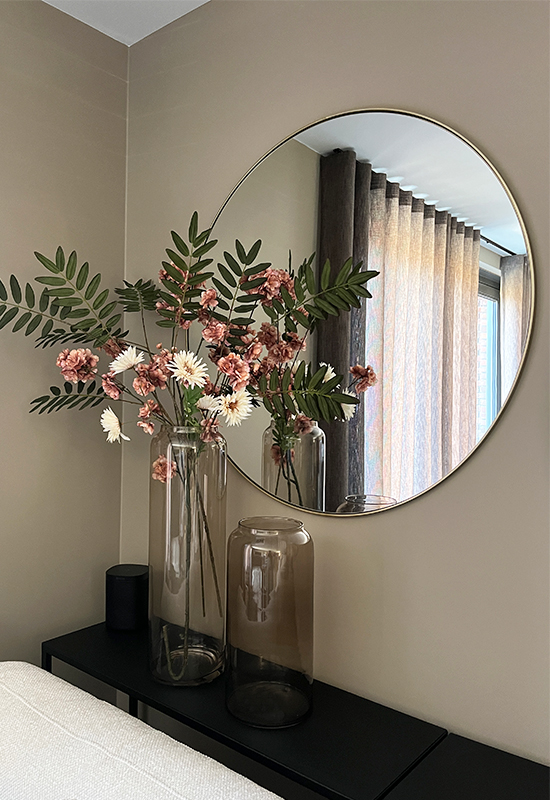 Twee hoge glazen vazen met roze en witte kunstbloemen ronde spiegel met gouden rand