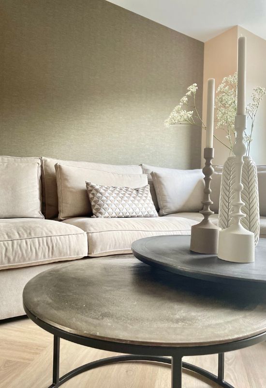 Beige hoekbank met lendenkussens bronzen ronde salontafelset bruine kandelaars japandi interieur