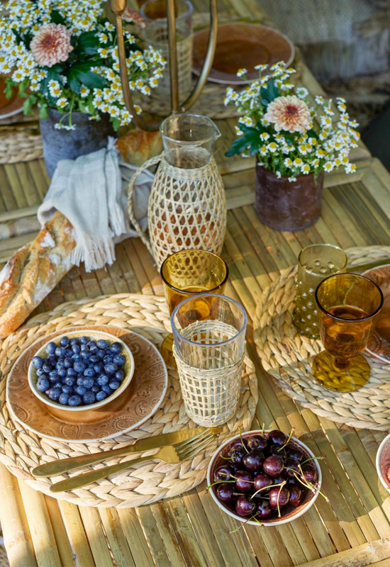 Houten buiten tafeltje gedekt ronde gevlochten placemats schaaltjes met fruit