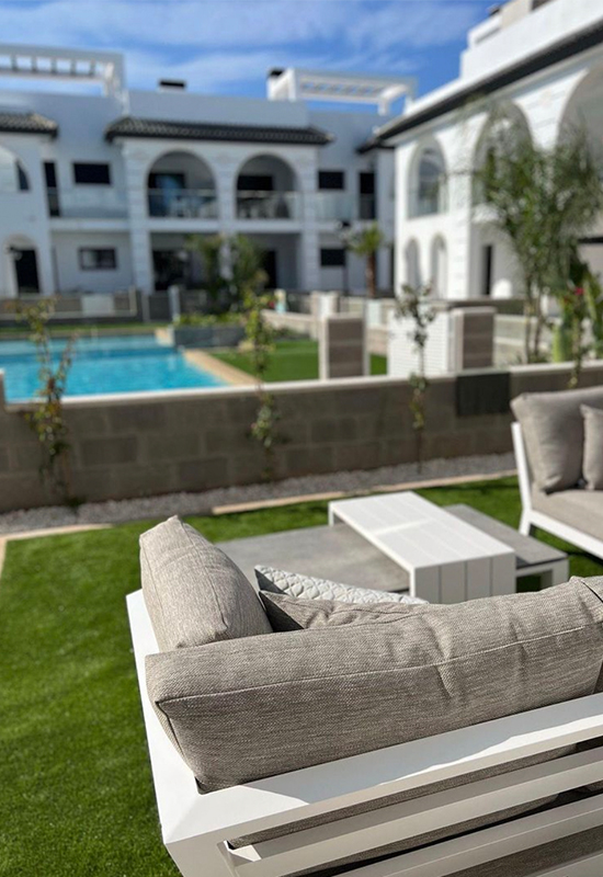 Witte loungeset met grijze kussens aan zwembad in Spanje