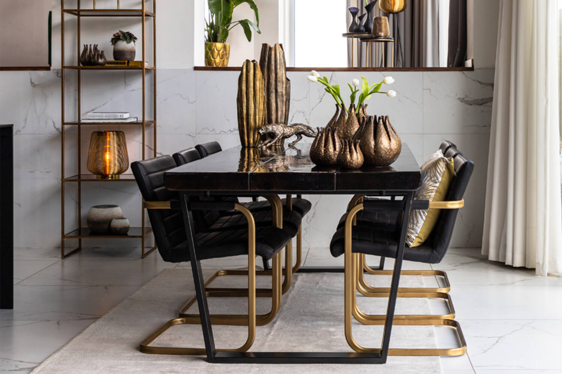 Zwarte eettafel zwart lederen eetkamerstoelen met gouden frame gouden vazen en ornamenten