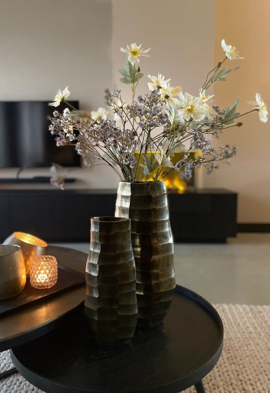 Zwarte ronde salontafel met bronzen hoge vazen met kunstbloemen