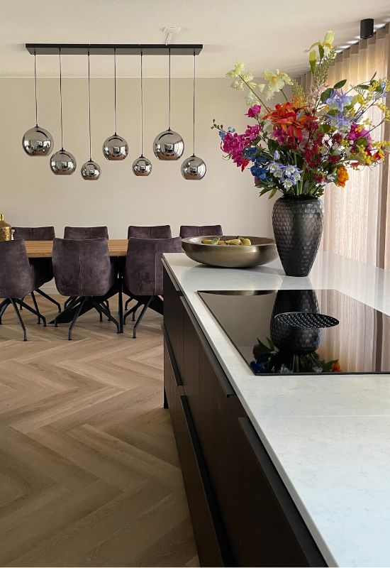 Zwarte keuken met wit marmeren aanrechtblad houten vloer grijze eetkamerstoelen