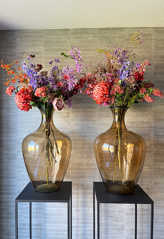 Zwarte zuilen met grote vazen met kunstbloemen boeket