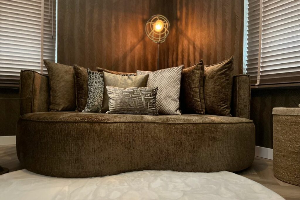 Bruine lounge fauteuil met ronde vormen en beige en bruine claudi sierkussens