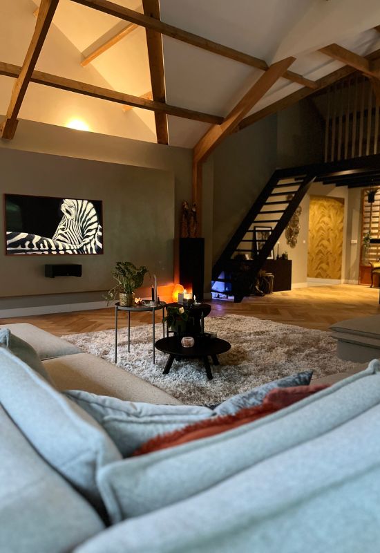 Woonkamer met houten balken drie salontafeltjes hoogpolig beige vloerkleed