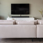 Stoffen beige hoekbank met rolletjes achter rugkussen