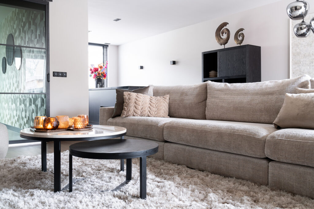 Zithoek met beige hoekbank en twee ronde salontafels