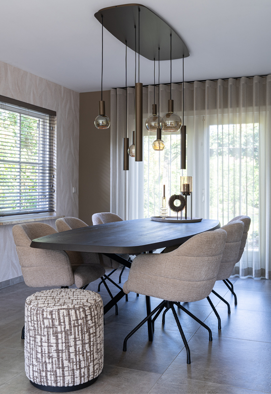 Eethoek met houten tafel en beige stoelen en speelse hanglamp